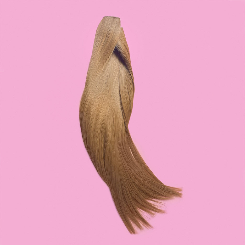 Big Glam Nation 21 inch extensions in sandy brown laid against pink background.