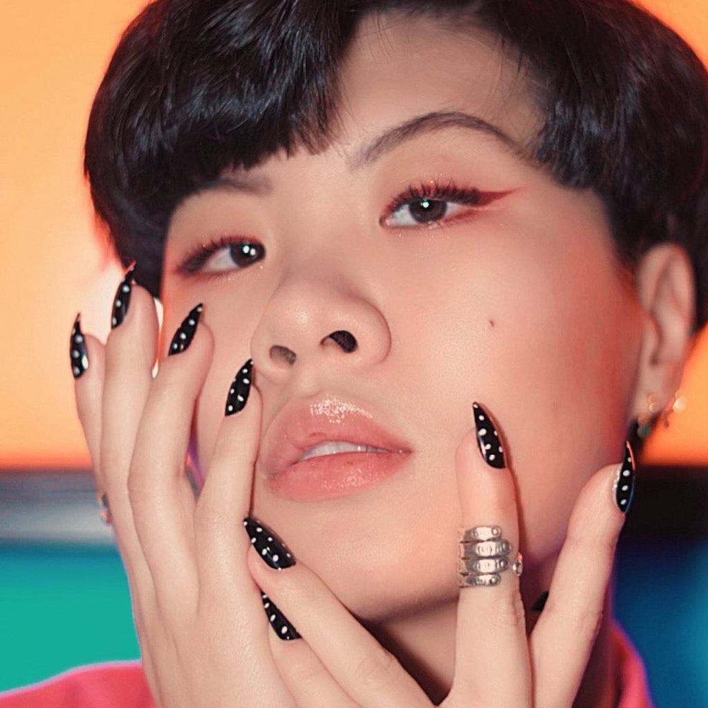 Faux nails in Big Glam Nation's Polkas modeled by fair skinned model in portrait style against retro background.