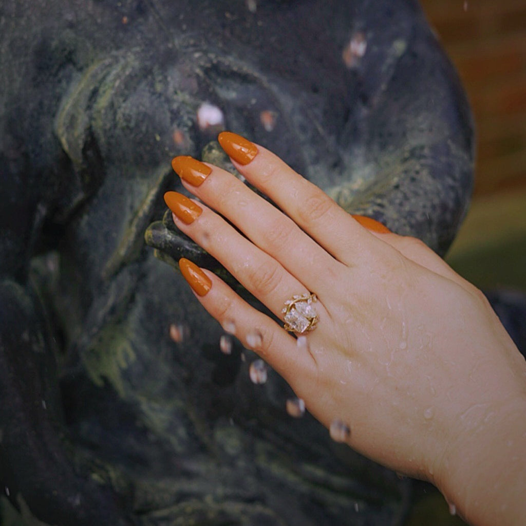 BGN's Press On Nails in ORANGE-SOLIDS worn on fair skinned models hand against scenic fountain.