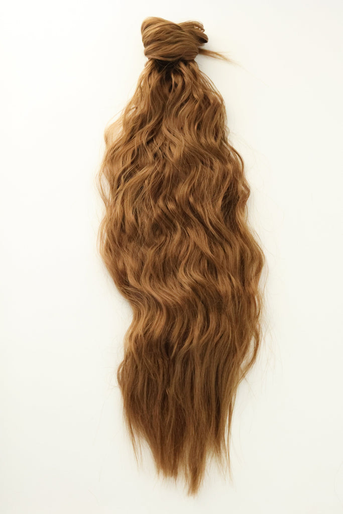 The Big Glam Nation crimped ponytail is laid flat on an off-white background. The ponytail has a wavy texture, in a ginger  brown color, with a velcro wraparound application.