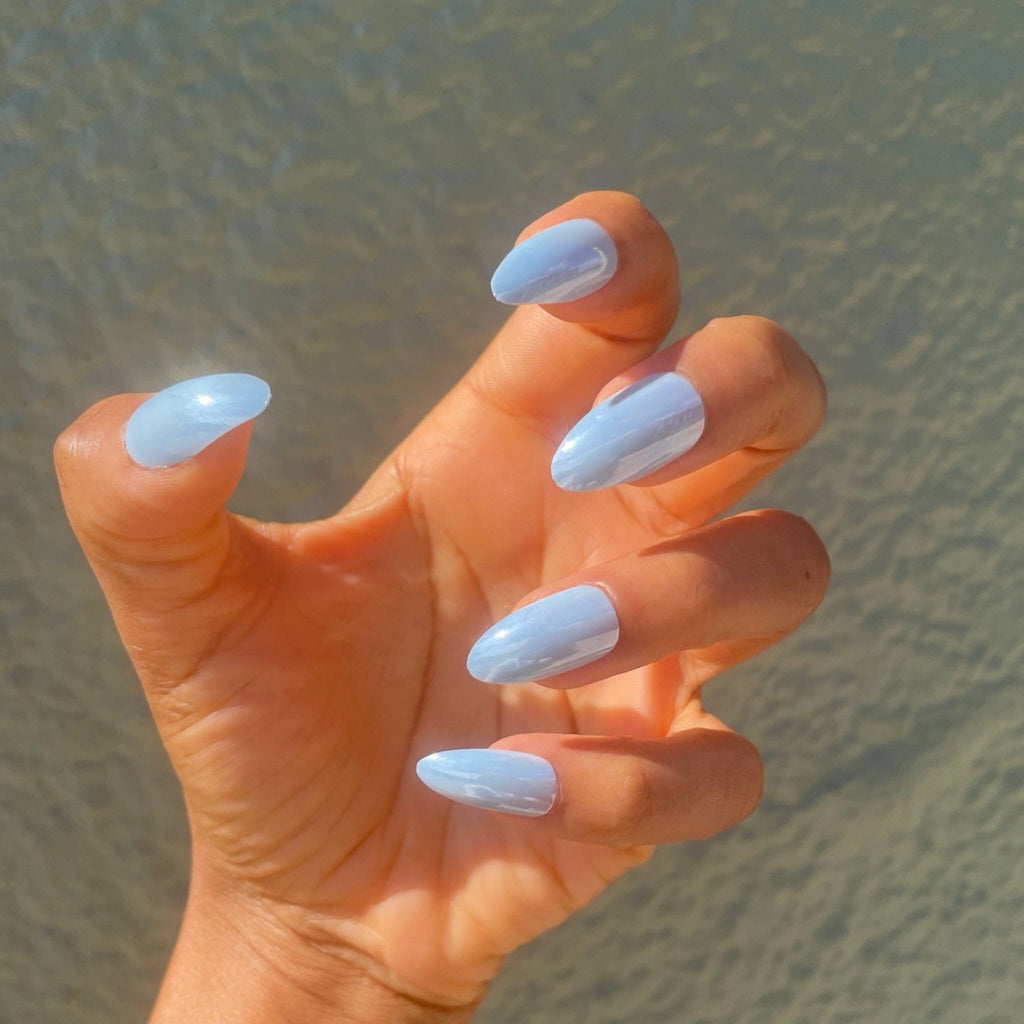 Press on nails in Big Glam Nation Cry Baby Blues modeled by brown skinned model against green colored wall.