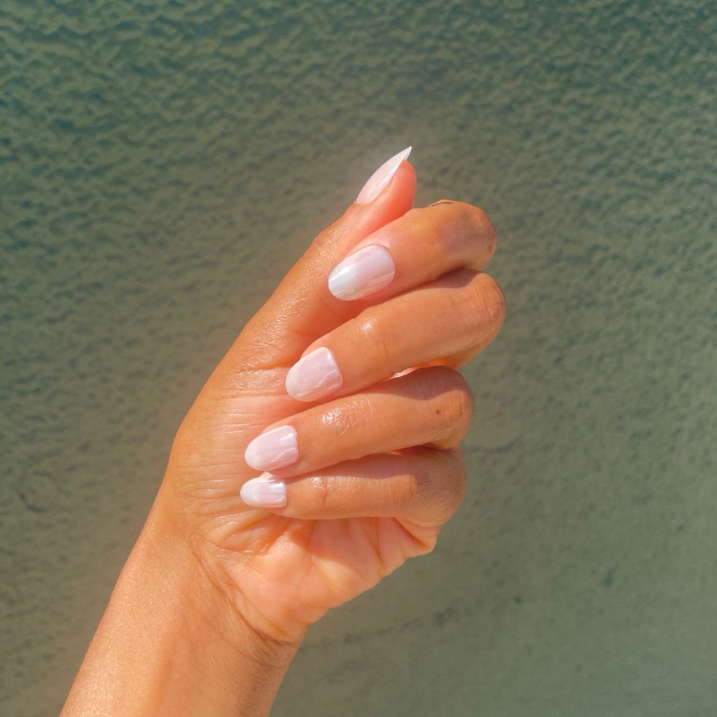 Reusable Manicure in Big Glam Nation's Tiny Pearls worn by brown skinned model against green/olive background.