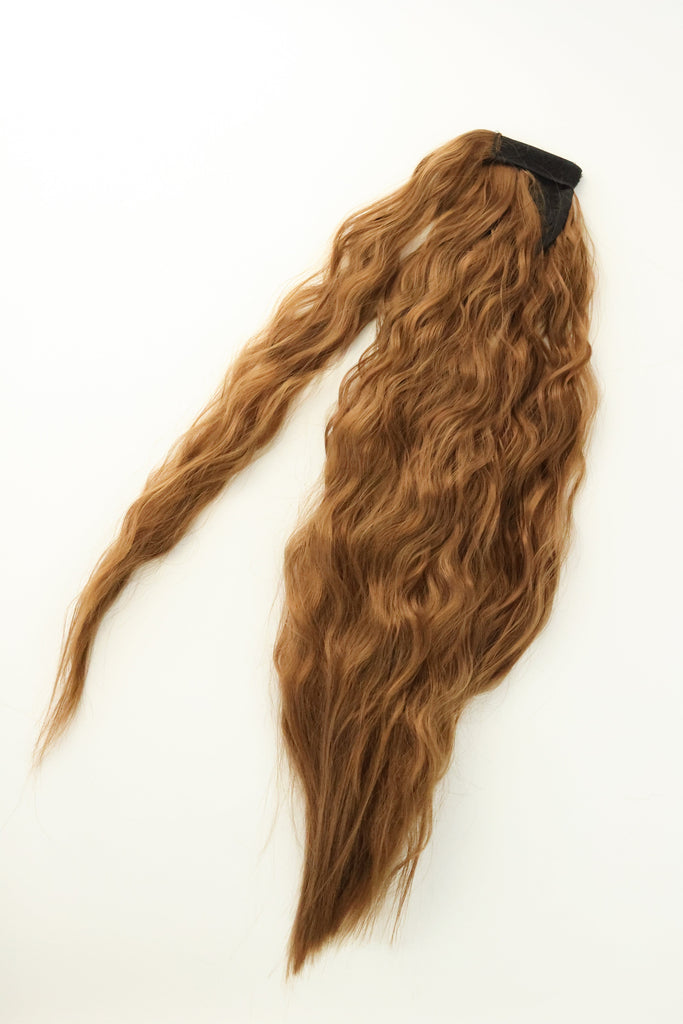 The Big Glam Nation crimped ponytail is laid flat on an off-white background. The ponytail has a wavy texture, in a ginger brown color, with a velcro wraparound application.