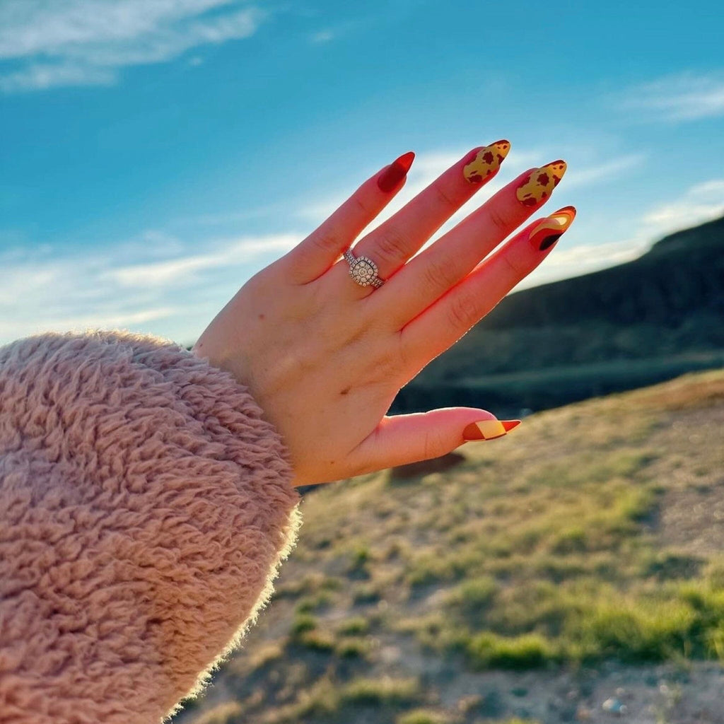 Press on Acrylic Nails in Big Glam Nation's Buttery Sherbet design worn by fair-skinned model against landscape background. 