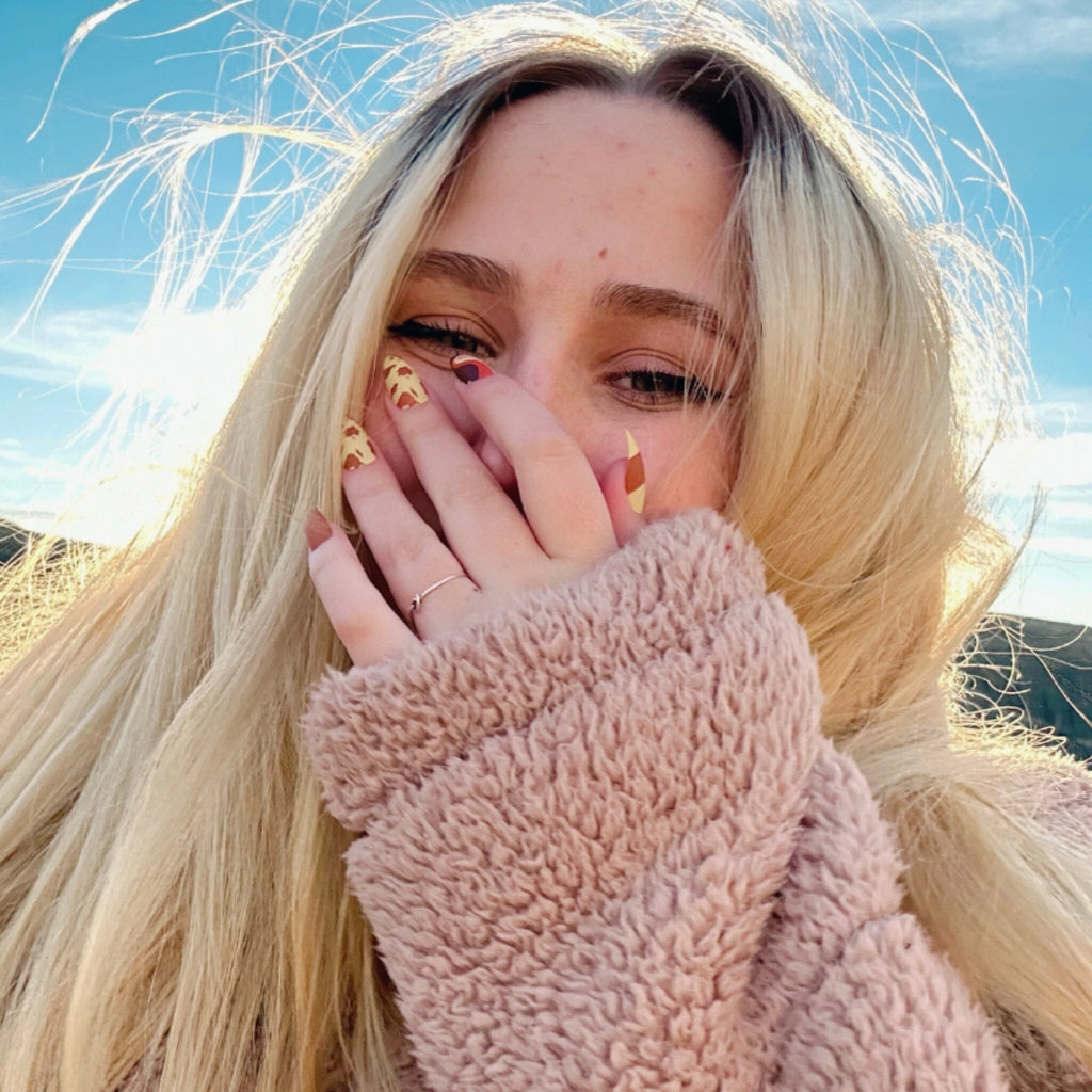 Fake Nails/Reusable Manicure in Big Glam Nation's Buttery Sherbet design worn by fair-skinned model against landscape background.