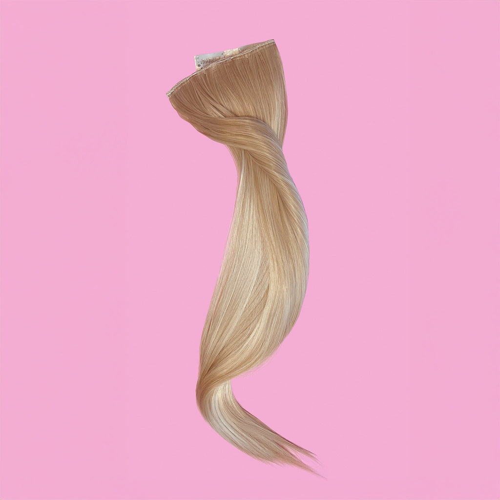 Big Glam Nation 21 inch extensions in Expensive Blonde laid against pink background.