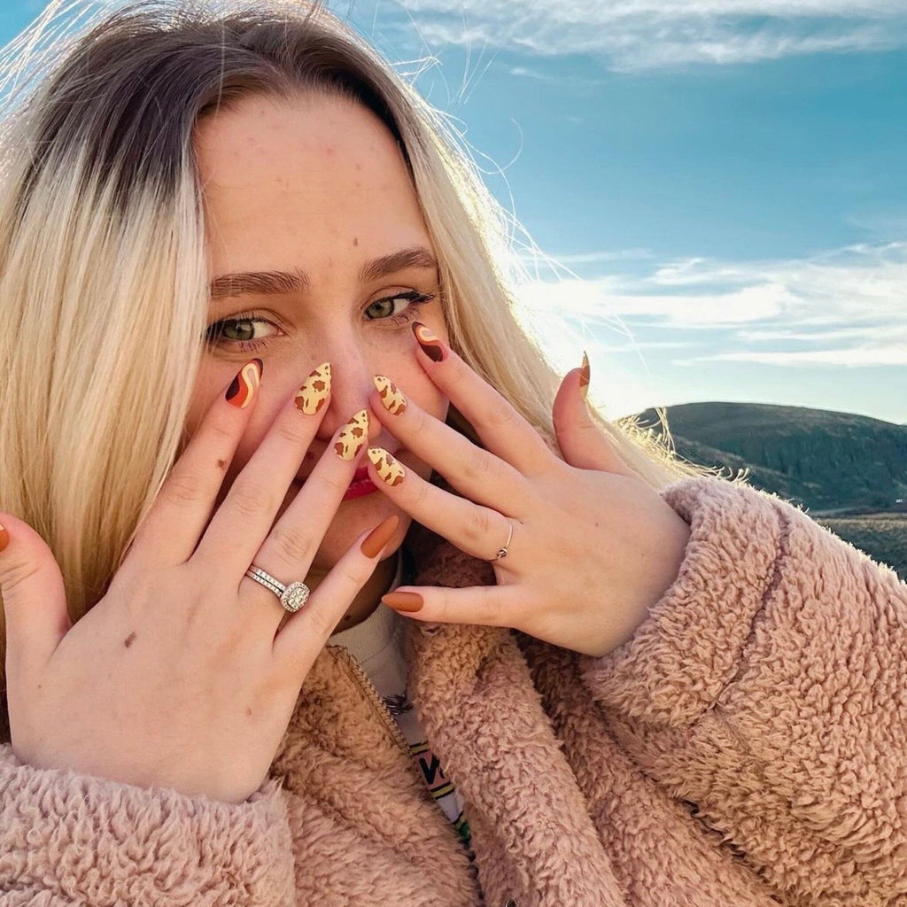 Press on Nails in Big Glam Nation's Buttery Sherbet design worn by fair-skinned model against landscape background. 