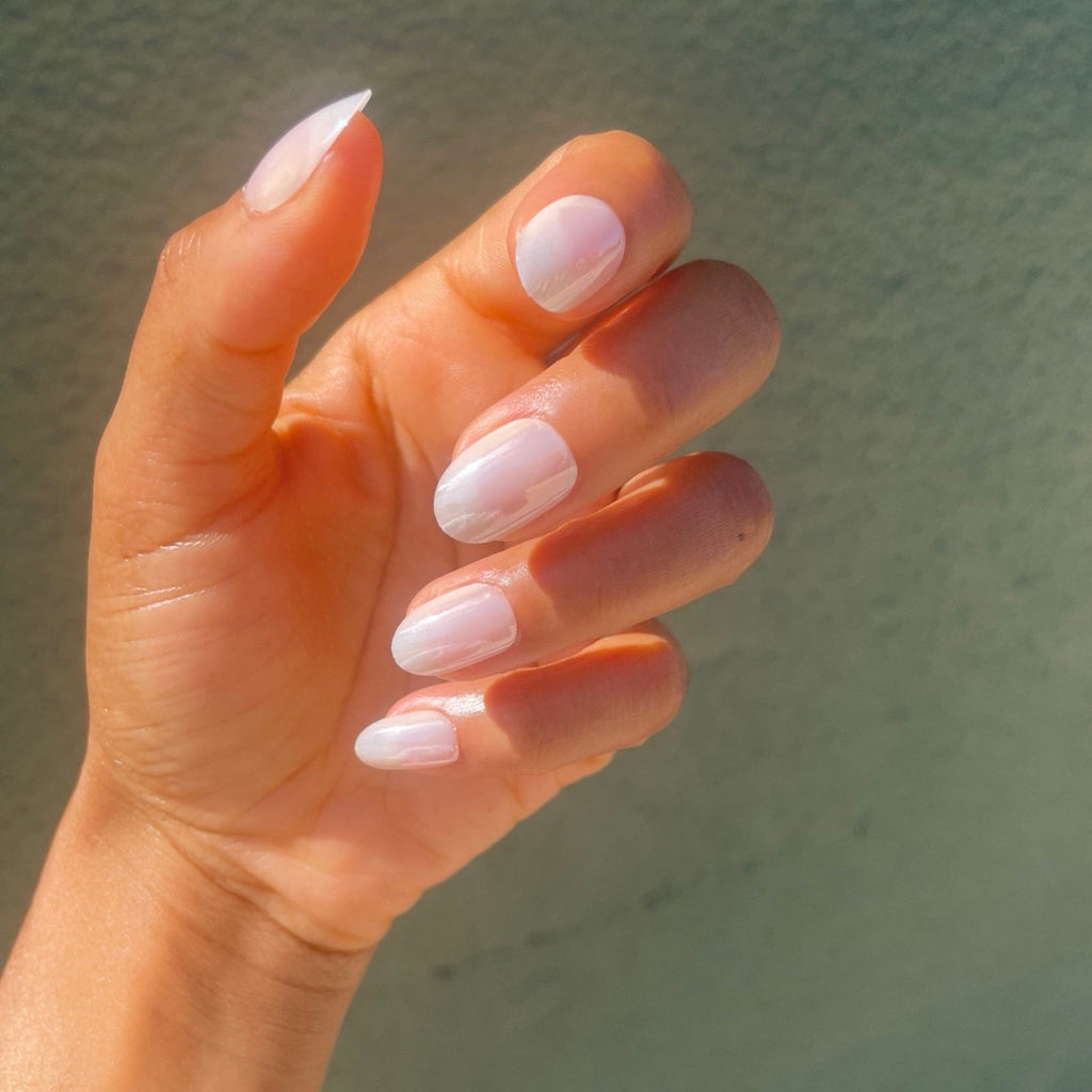 Faux Nails in Big Glam Nation's Tiny Pearls worn by brown skinned model against green/olive background.