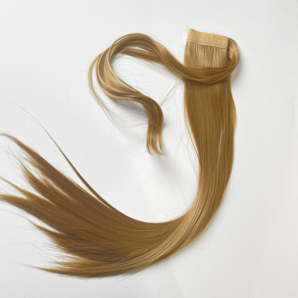 The Big Glam Nation Sleek Ponytail is laid flat against a white background in the color Sandy Brown. Length and shine of the extensions are highlighted.