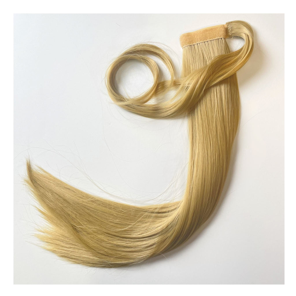 The Big Glam Nation Sleek Ponytail is laid flat against a white background in the color Beach Sand Blonde. Length and shine of the extensions are highlighted.