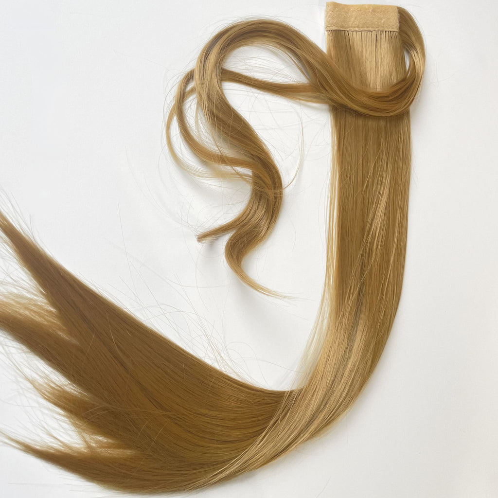 The Big Glam Nation Sleek Ponytail is laid flat against a white background in the color Sandy Brown. Length and shine of the extensions are highlighted.