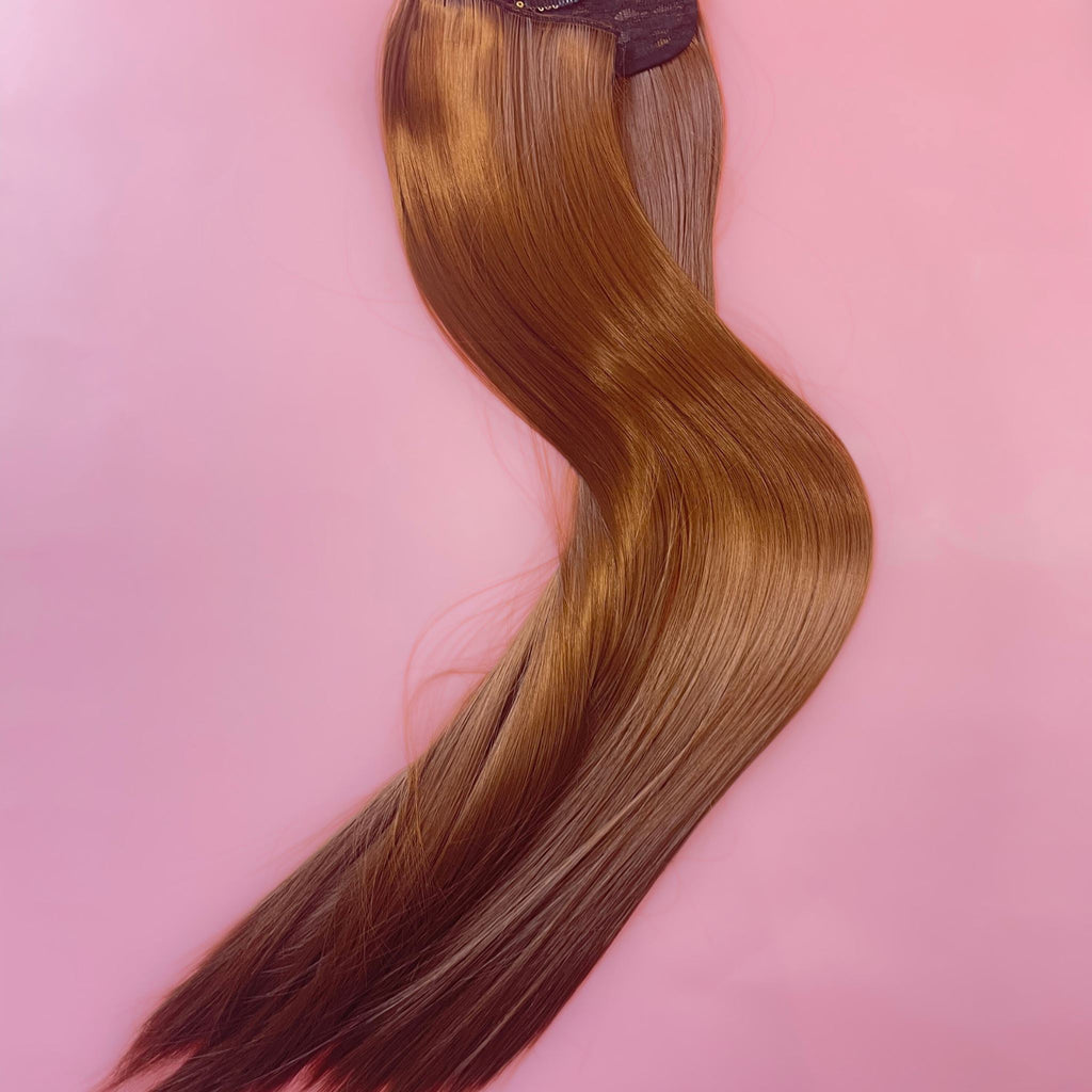 Big Glam Nation 21 inch extensions in Vibrant Brown laid against pink background.